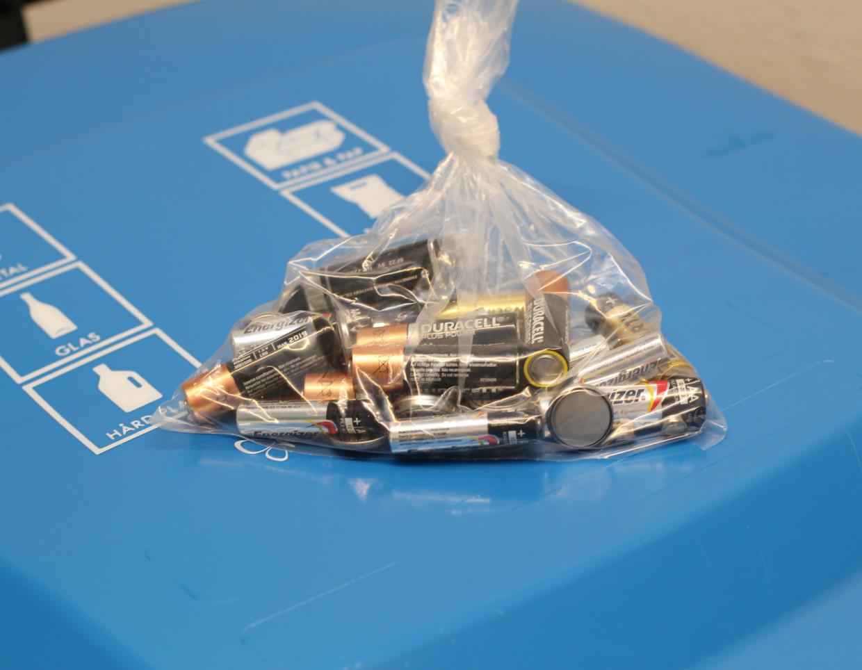 Batterier placeres i en pose på låget af en skraldespand